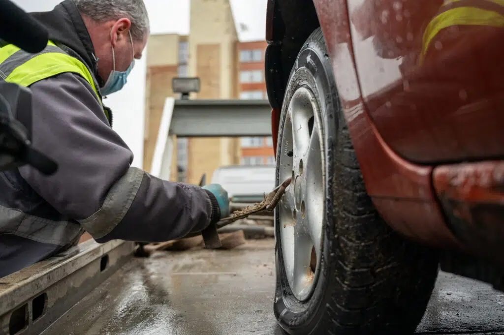 technines pagalbos darbuotojas tvirtina lengvaji automobili ant tralo