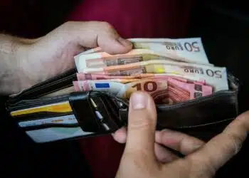 vyras laiko pinigine su euro banknotais viduje