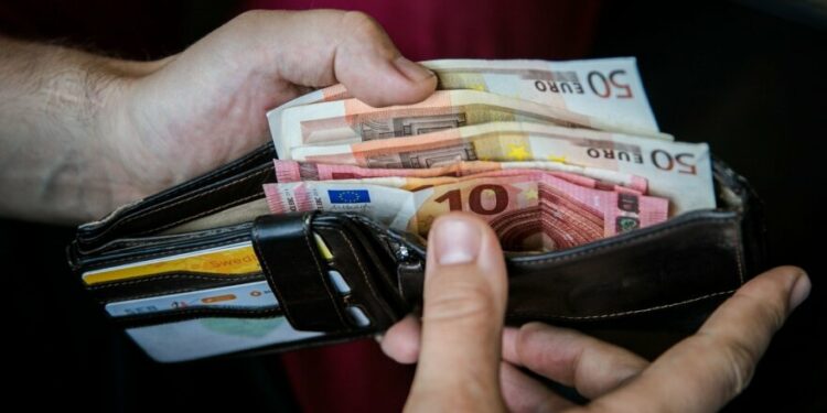 vyras laiko pinigine su euro banknotais viduje