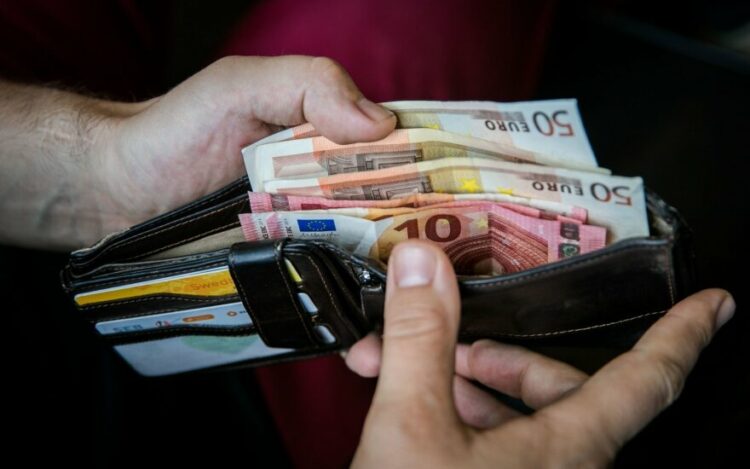 vyras laiko pinigine su euro banknotais viduje