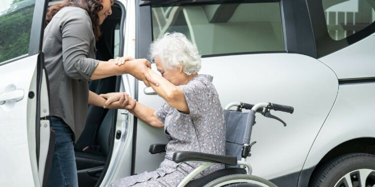 moteris padeda senyvo amziaus moteriai isesti i automobili