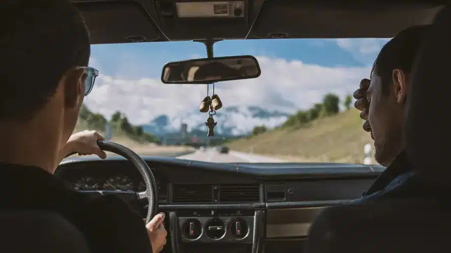 du vyrai vairuotojas ir keleivis vaziuoja automobiliu
