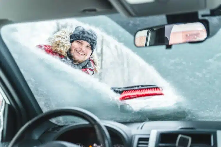 vyras valo priekini automobilio langa nuo sniego
