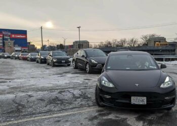 tesla elektromobiliai laukia eileje prie ikrovimo stoteliu