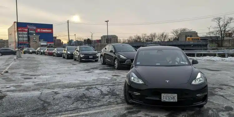 tesla elektromobiliai laukia eileje prie ikrovimo stoteliu