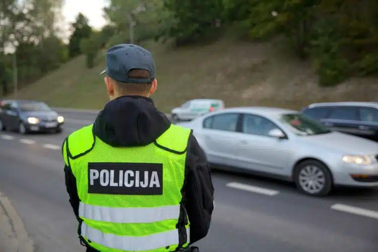 policijos pareigunas stebi eisma automobiliai