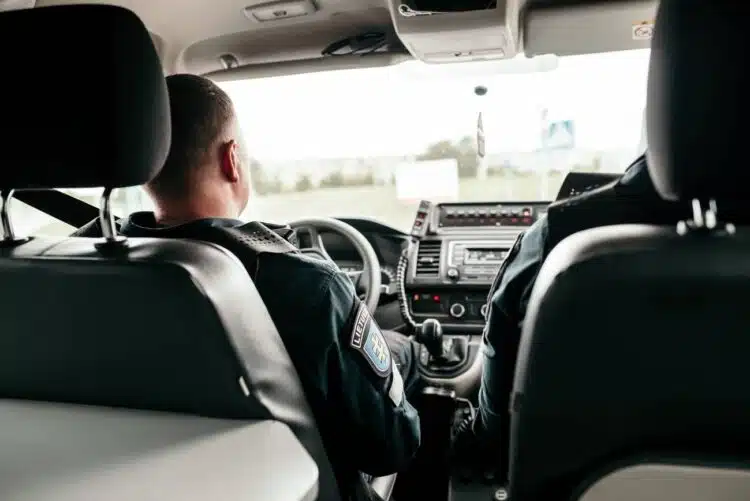 policijos pareigunai sedi policijos tarnybiniame automobilyje