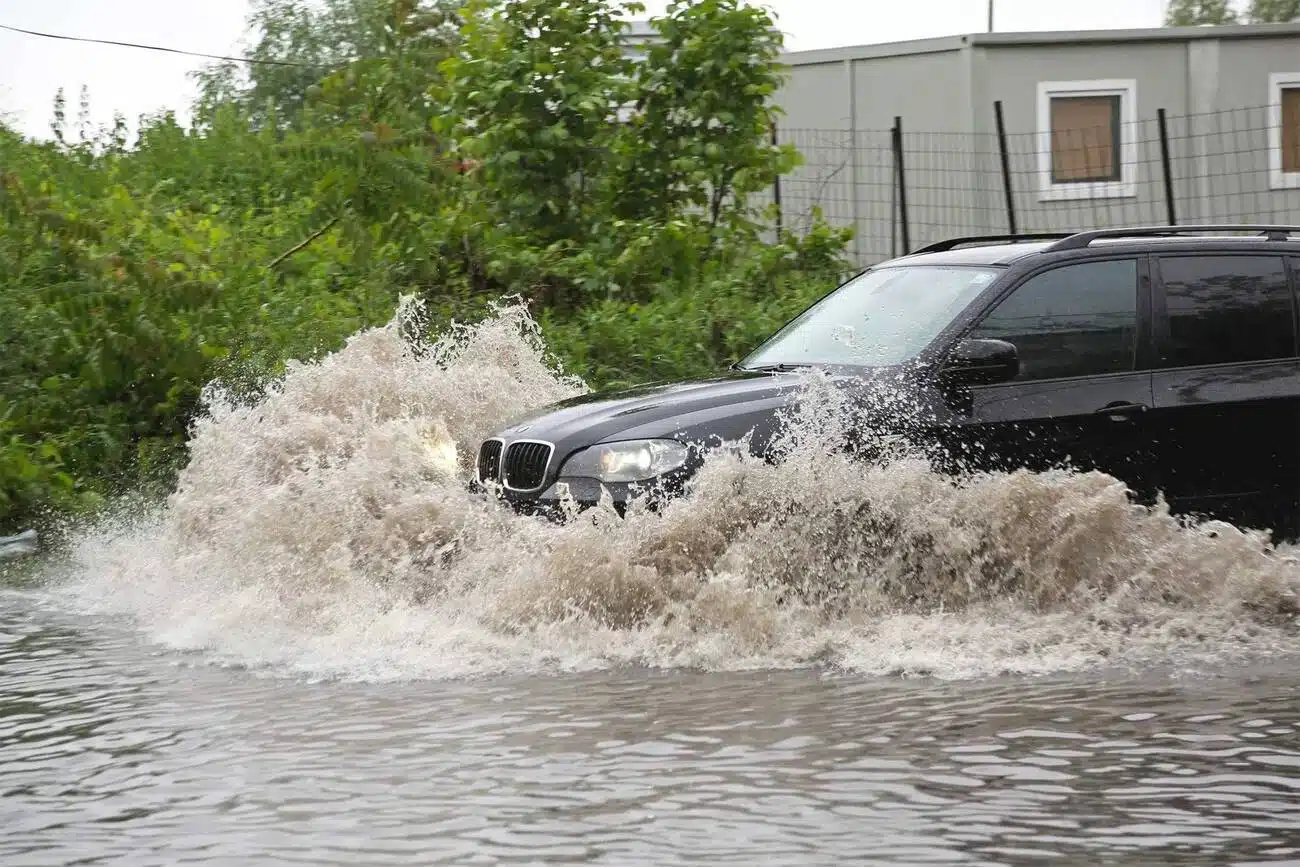 Visureigiai su didele bagažine: juodas BMW X5 visureigis važiuoja per didelę balą
