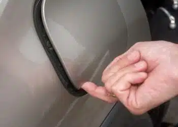 automobilio degalu bako dangtelis prispaustas pirstas