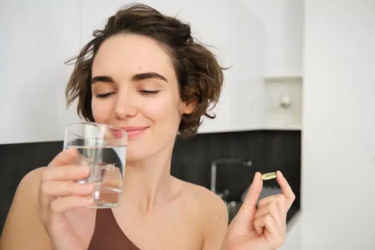 moteris laiko stikline su vandeniu tablete vitaminai selenas