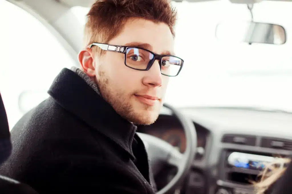 Automobilyje sėdintis jaunas vyras su akiniais stambiu planu vairuotojas su akiniais