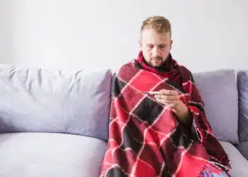 Vyras po antklode su termometru gripas skaidulos skaidulines medziagos