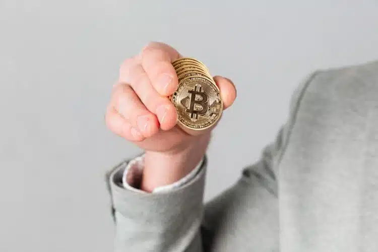 Vyriškos rankos rodančios auksinį bitkoiną vaizdas iš arti bitcoin