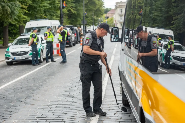 pareigunas tikrina transporto priemones apacia su veidrodziu