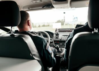 policijos pareigunai vaziuoja tarnybiniame automobilyje