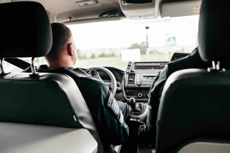 policijos pareigunai vaziuoja tarnybiniame automobilyje
