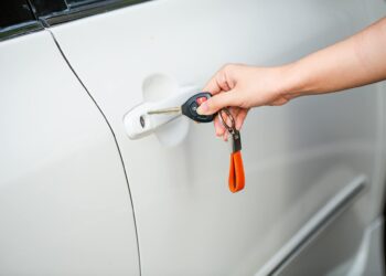 Asmuo laikantis automobilio raktą prie automobilio durų