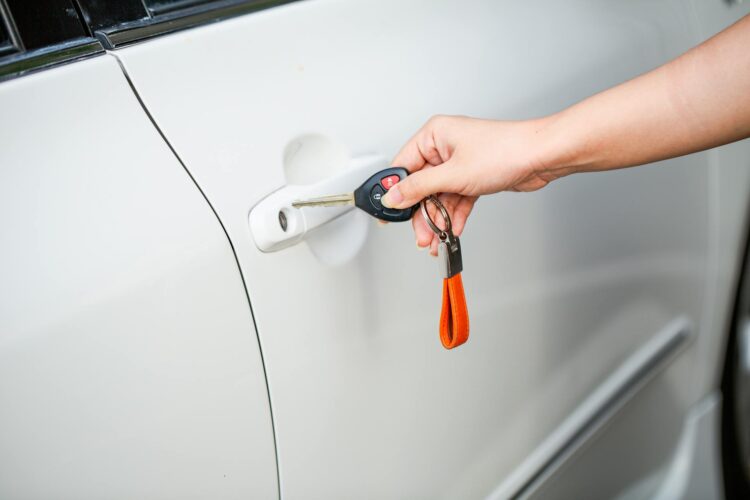 Asmuo laikantis automobilio raktą prie automobilio durų