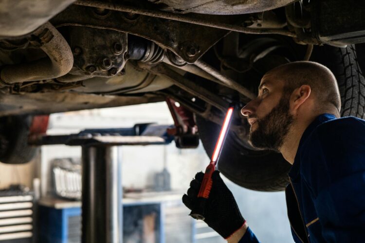 Vyras tikrinantis automobilio važiuoklę