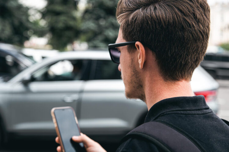 Jaunas vyras su akinais nuo saulės artimas planas kaip jis naudoja išmanųjį telefoną nuotrauka foto