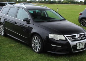 Juodas Volkswagen Passat R36 universalas iš priekio ir šono, stovintis ant žolės