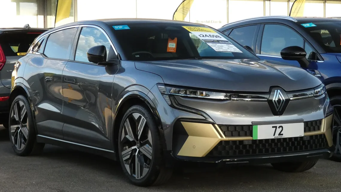 Prancūziško sedano pirkėjams nebeliko benzininės versijos – elektrinis įpėdinis talpesnis tik su viena sąlyga 1 Renault Megane E-Tech: pilkas elektrinis krosoveris su auksiniais buferio intarpais iš priekio ir šono