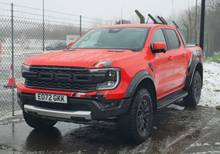 Pirkdami naudotą sportinį pikapą galite netekti didžiausio jo pranašumo – jei nepažiūrėsite po juo 1 Ford Ranger Raptor: raudonas naujos kartos pikapas iš priekio ir šono šlapioje aikštelėje žiemą