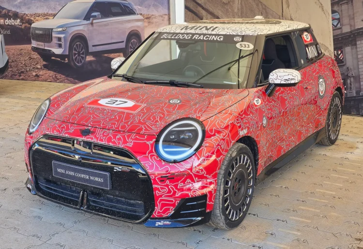 Sportiškiausios mažo elektromobilio versijos pirkėjams – testuotojas įvardijo, kas joje erzina labiausiai 1 Mini JCW Electric raudonu raštuotu apvalkalu su John Cooper Works numerio lentele parodos stende