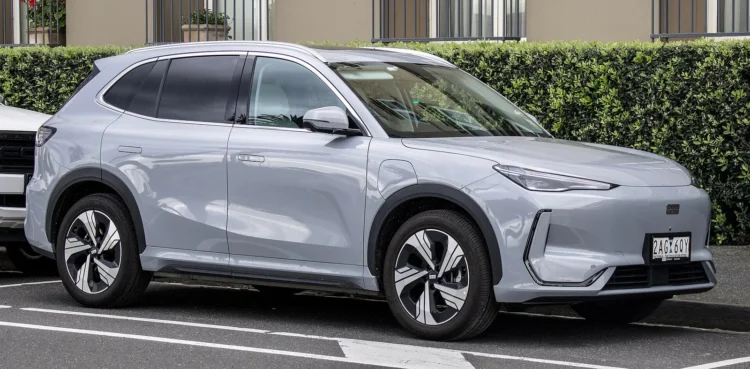 Kiniškas elektromobilis, kuriamas Europos vairuotojams, pasirodys 2027-aisiais 1 Geely elektromobilis Europai: pilkas Geely EX5 krosoveris iš priekio ir šono stovi lauko aikštelėje