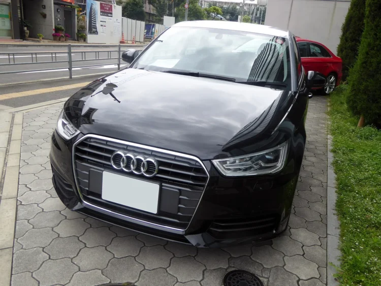„Audi A1“ su litro varikliu pirkėjams – viena kėbulo detalė kainuoja apie 840 eurų 1 Juodas Audi A1 Sportback 1.0 TFSI po atnaujinimo iš priekio, stovintis ant trinkelių grindinio