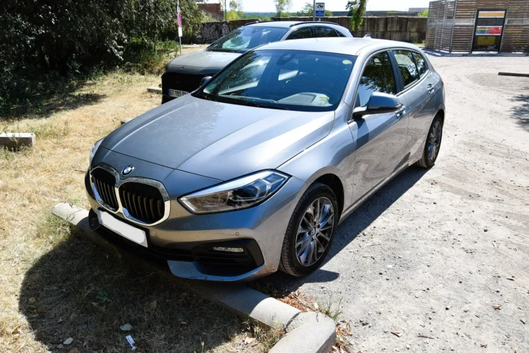 Penkerių metų „BMW 1 serijos“ pirkėjams – be šių įrašų serviso istorijoje galite netekti turbinos 1 Naudota BMW 1 serija F40: pilkas hečbekas iš priekio ir šono, stovintis aikštelėje prie žolės