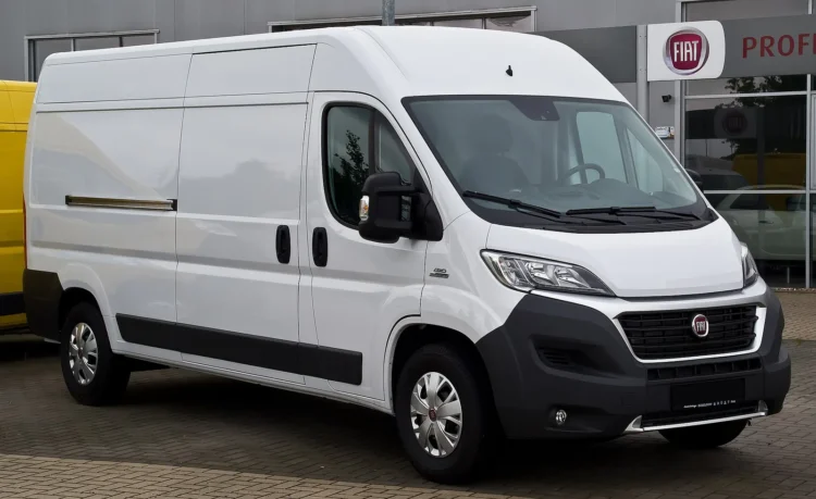 Baltas Fiat Ducato krovininis furgonas iš priekio ir šono, stovintis prie prekybos salono