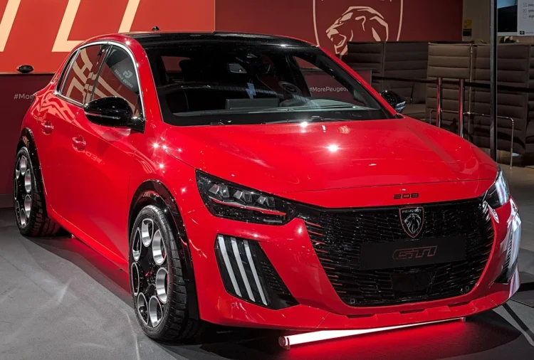 Raudonas Peugeot E-208 GTi hečbekas iš priekio ir šono parodoje