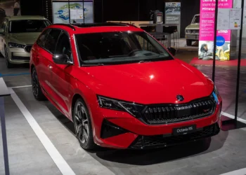 Hibridinės Octavia kaina: raudonas atnaujintas Škoda Octavia Combi universalas iš priekio ir šono parodos stende