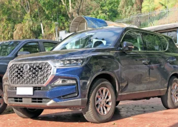 Tamsiai mėlynas KGM (SsangYong) Rexton visureigis iš priekio ir šono, stovintis aikštelėje